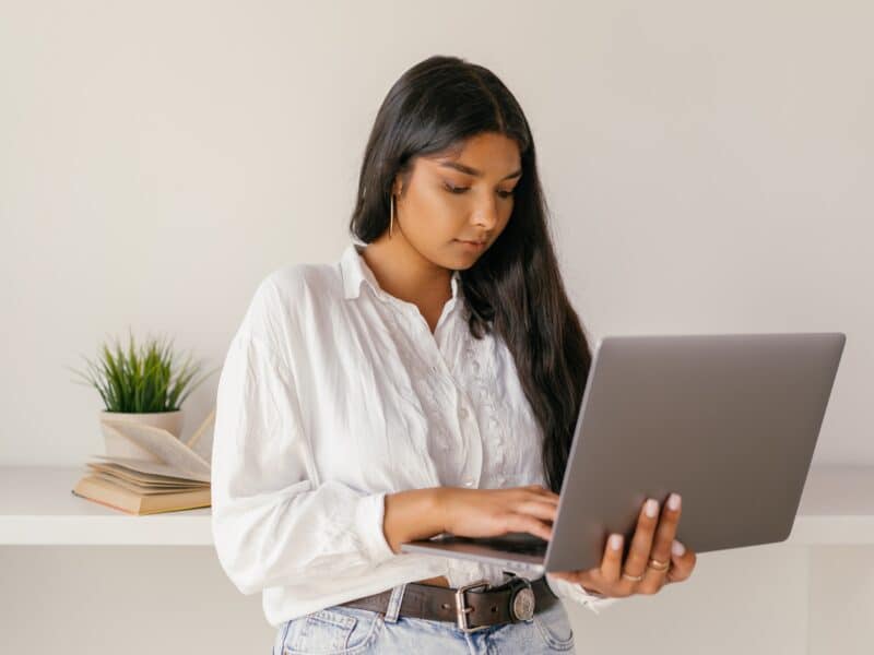 A woman in a white dress shirt using a laptop. Email series.