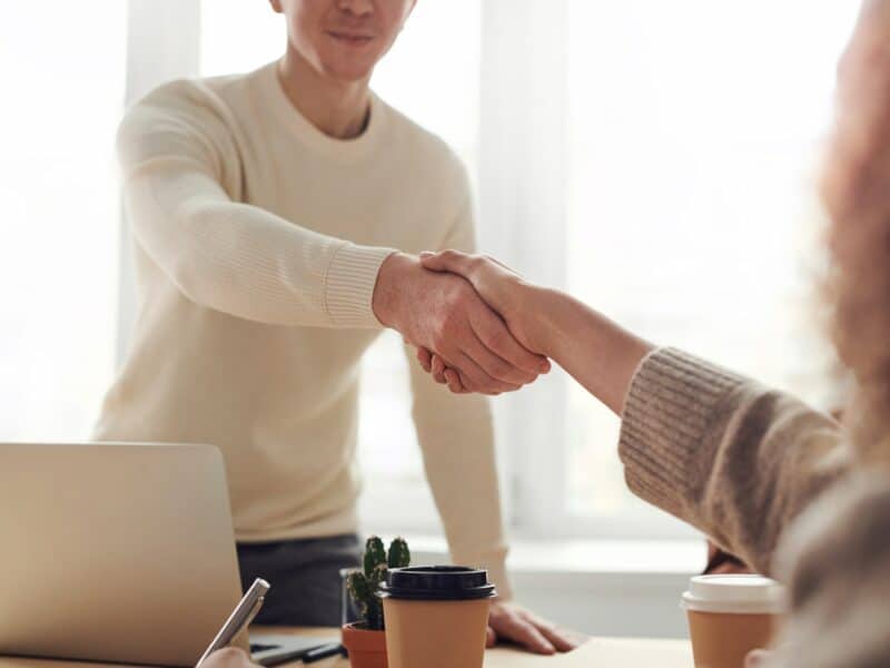 Man and woman shaking hands over a table.